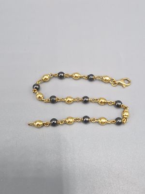 un collier composé de perles dorées et noires, muni d'un fermoir doré