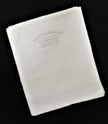 serviette blanche sur laquelle est brodée une couronne sur fond noir