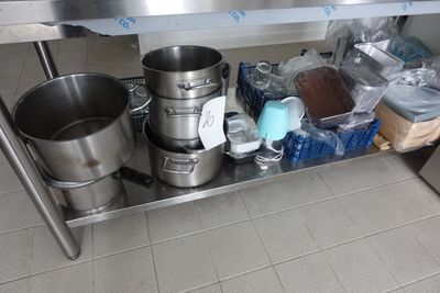 une table en acier inoxydable sur laquelle sont posés des casseroles et des poêles