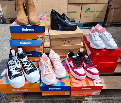 Plusieurs paires de chaussures sont empilées sur des cartons posés sur une palette
