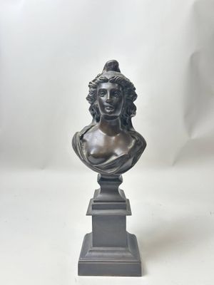 un buste en bronze représentant une femme, posé sur un socle