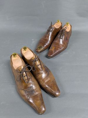 two pairs of brown shoes with laces on them on a gray surface
