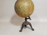 un globe en laiton ancien posé sur un trépied, avec un fond blanc