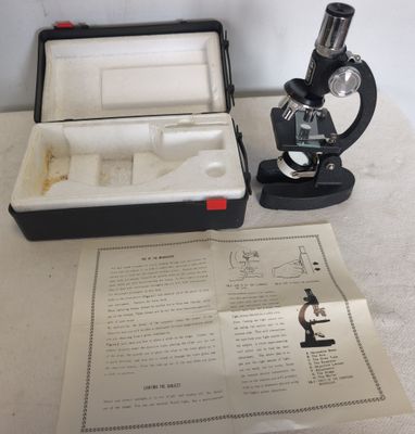 un microscope posé sur une table, à côté d'une feuille de papier