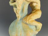 une sculpture en céramique représentant une femme assise sur un vase