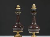 une paire de vases rouges et dorés posés sur une table blanche