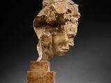 a sculpture of a head of a woman on a wooden block