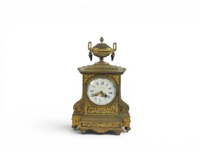 a gold clock with a white face on a white background