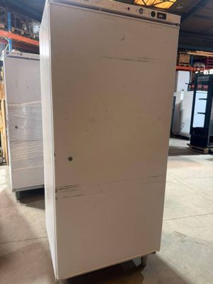 un réfrigérateur blanc posé dans un entrepôt, avec d'autres appareils électroménagers en arrière-plan