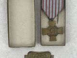medal in a box with a ribbon and a tag on a white surface