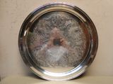 un plateau en argent orné de l'image d'une femme en robe blanche