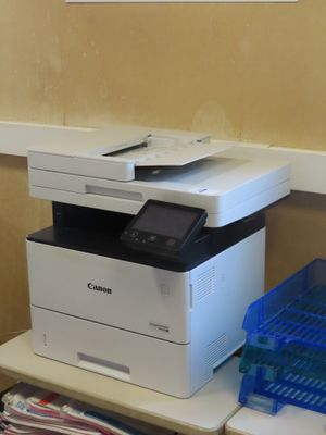 une imprimante posée sur un bureau, à côté d'une pile de magazines