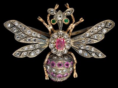 un gros plan sur une broche en forme d'abeille ornée de pierres roses, vertes et blanches