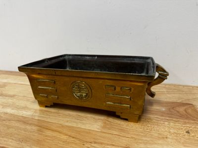 un petit récipient en métal posé sur une table en bois