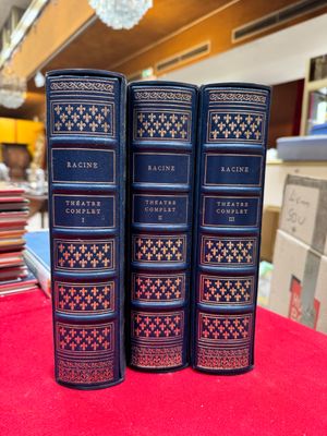 trois livres bleus posés sur une table recouverte d'un tissu rouge