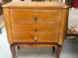 a small wooden chest of drawers in the middle of a room