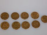 a group of six gold sovereigns sitting on top of a white surface