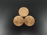 three gold coins sitting on top of each other on a black surface