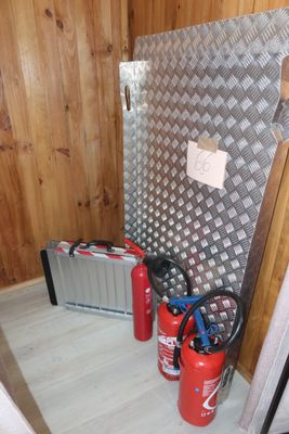 two fire extinguisors and a tool case in the corner of a room