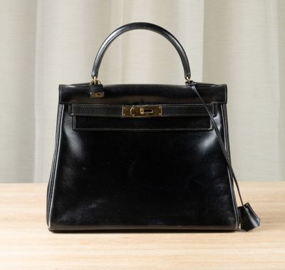 a black leather handbag sitting on top of a wooden table