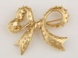 Broche en forme de nœud, couleur or jaune, ornée de strass et de perles