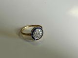 a close up of a diamond and sapphire ring on a white surface