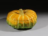 une boîte en forme de citrouille, jaune et verte, posée sur une table