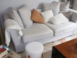 a white couch with many pillows on it in a living room