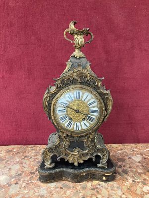 a clock that is sitting on a table with a red wall in the background