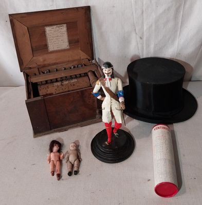 un chapeau, un haut-de-forme, une poupée et d'autres objets posés sur une table