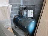 un compresseur d'air installé dans une pièce, à côté d'un tas de bois