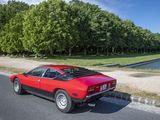a red sports car driving down the road by the water