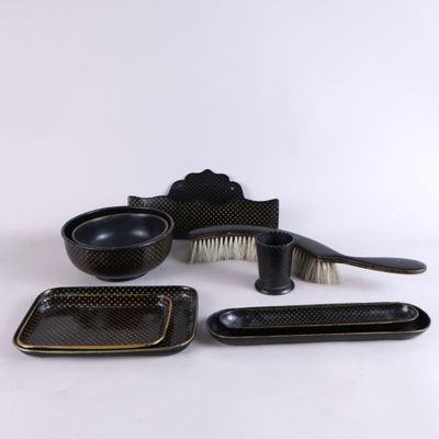 an assortment of black and gold dishes and brushes on a white background