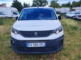 La camionnette blanche est garée dans l'herbe, devant d'autres véhicules.