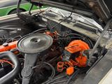a car engine with its hood open and a car in the background