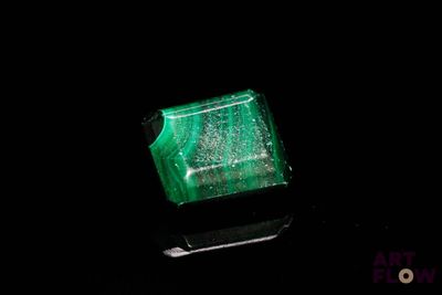 un gros plan d'un anneau vert sur une surface noire