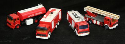 Quatre camions de pompiers miniatures sont alignés en rang sur une surface noire
