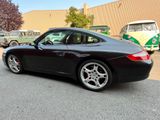 a black porsche parked in a parking lot next to a bus