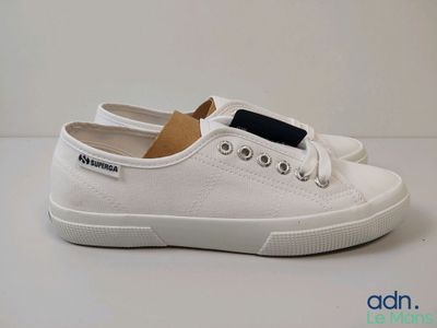 les chaussures blanches sont posées sur une surface blanche ornée d'une bande noire