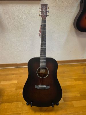 an acoustic guitar sitting on top of a hard wood floor next to a wall