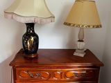 a lamp on a dresser next to a lamp on a table