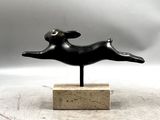 statue d'un chien bondissant, posée sur un socle en marbre, sur fond gris