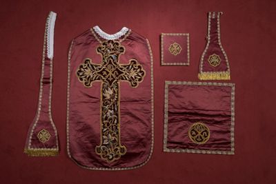 une image représentant les vêtements et les accessoires d'un prêtre sur fond rouge