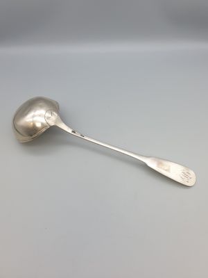 une cuillère en argent dont le manche repose sur une table
