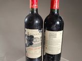 two bottles of red wine sitting on a clear table
