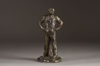 bronze statue of a man standing on a rock with his hands on his hips