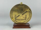 a brass compass on a wooden stand with a white background