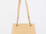 a beige quilted bag with a gold chain handle