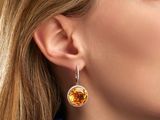 close up of a woman wearing a pair of earrings with a citrine stone