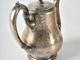 a silver tea pot with a handle on a table